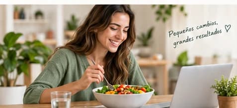 Mujer comiendo una ensalada saludable mientras utiliza su computadora